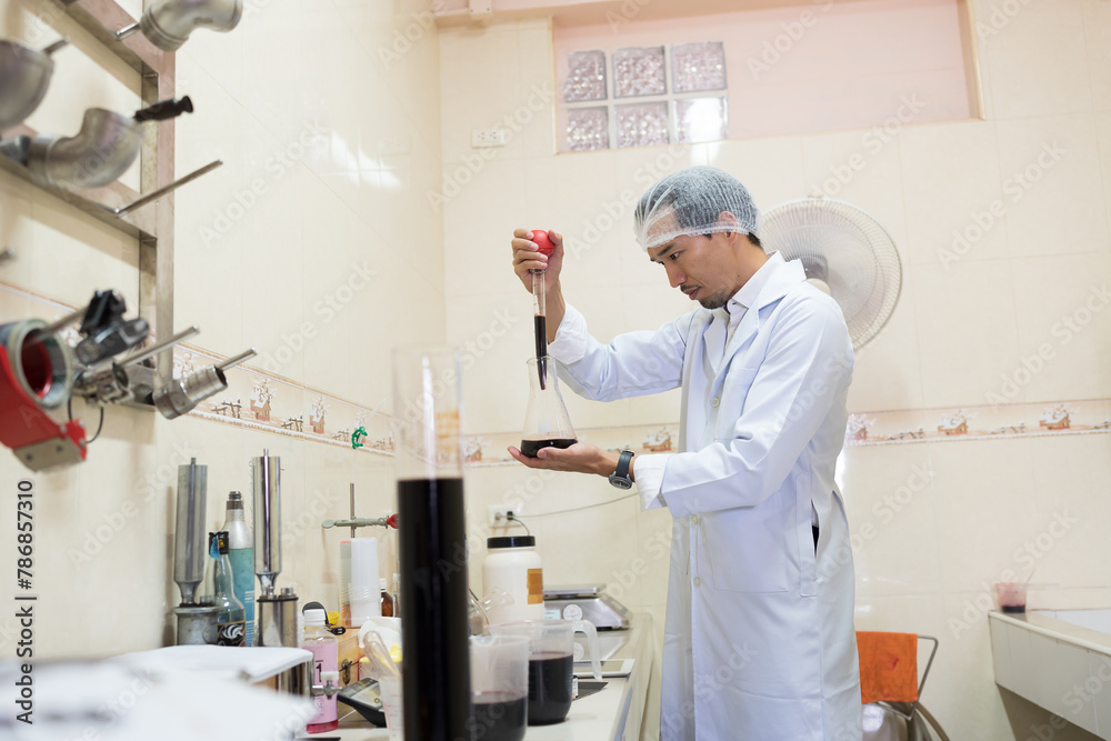 Winemaker inspecting quality of wine during manufacturing in winery factory. Male winemaker working in winery factory Winemaker inspecting quality of wine during manufacturing in winery factory. Male winemaker working in winery factory
