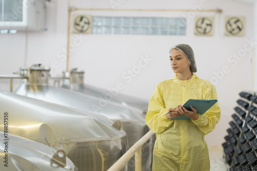 Female factory worker inspecting quality of wine bottles during manufacturing in process in fermentation wine factory. Wine manufacturing industry concept