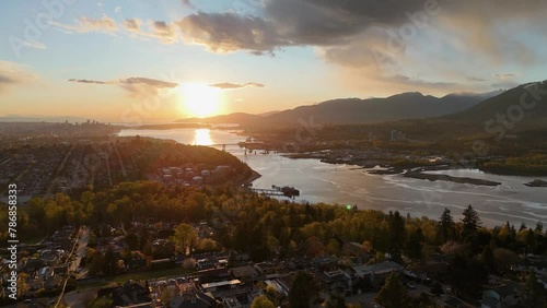 Panoramic aerial drone view (pan right) of the sunset over the skyline of Vancouver, Burnaby, and the Burrard Inlet during a spring season in British Columbia, Canada