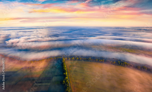 Cultivated fields covered by thick fog. Funtastic rural scene of Ukrainian countryside at sunrise. Misty summer morning in Ternopil region, Ukraine, Europe. Foggy sunrise with endless horizon...