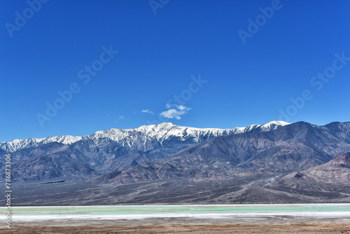 The green waters of the lake at Devils Golf Course with the snowcapped Black Mountains in the background, Death Valley National Park.