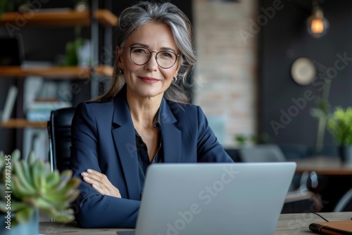 Smiling mature adult business woman executive sitting at desk using laptop. Happy busy professional mid aged businesswoman ceo manager working on computer corporate technology in office