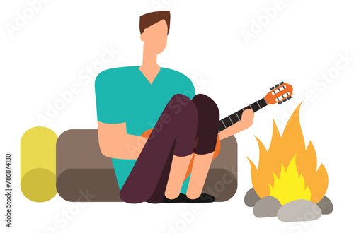 a man on a hike near a fire plays the guitar