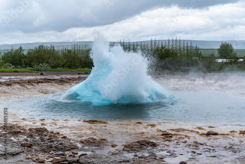 Geysir Strokkur in Island bricht aus, heißes türkises Wasser spritzt hoch, Naturwunder in Europa