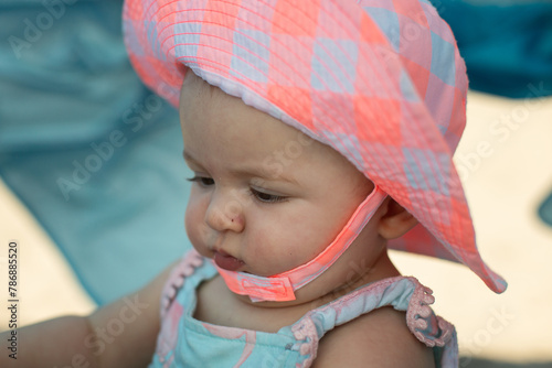 Fotografija Baby with chubby cheeks at the beach wearing sun hat