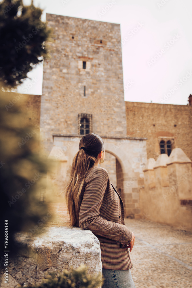 Brunette girl observing the entrance of a medieval castle in Perpignan