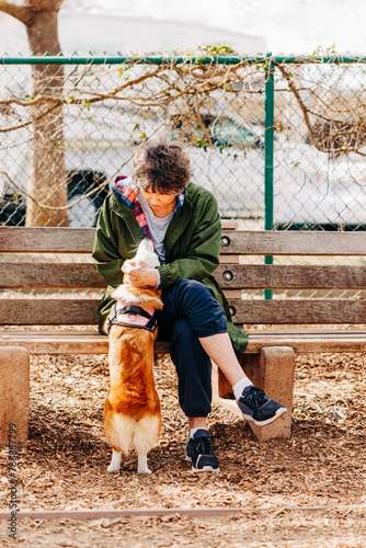 Woman sitting on bench at dog park petting dog