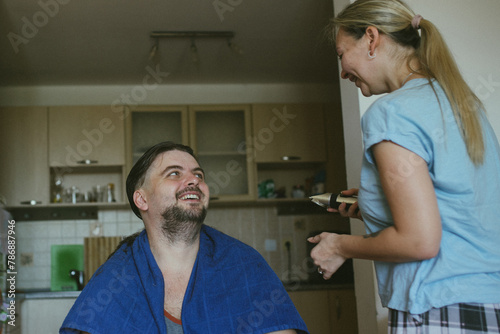 Wife gives her husband a funny haircut with a trimmer.