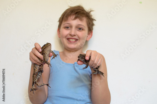 Boy holding a big toad in his hands. two frogs