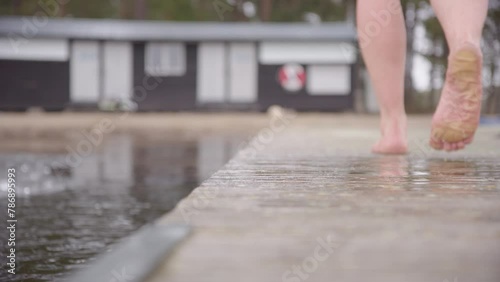 Closeup female ice bathers feet, as she walks away down the pontoon photo