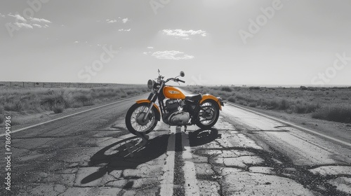 Black and white desert road with a yellow motorcycle in the middle. photo