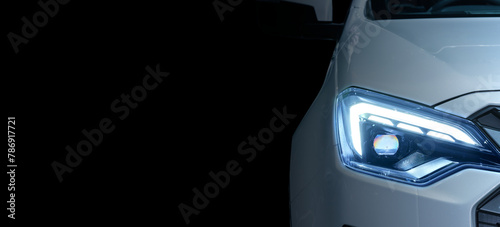 Close-up front left eyesight headlight with LED xenon light of white luxury modern car on black colour background and left copy space for text or message