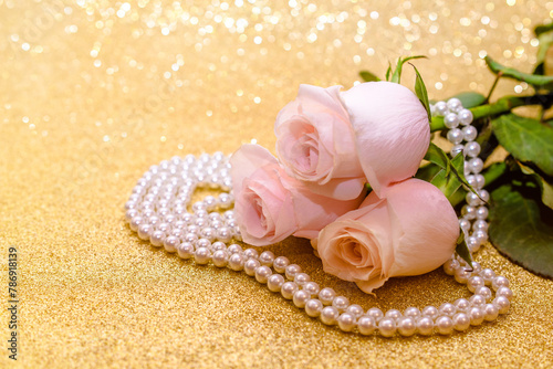 Pink rose and pearl necklace on a shiny gold background