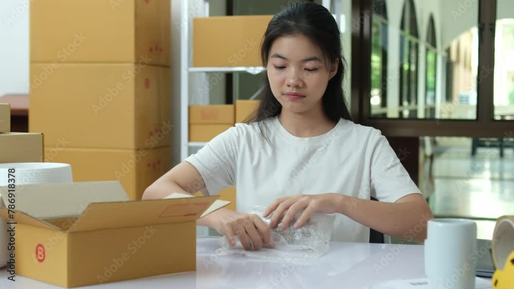 Entrepreneur in home office packing products into cardboard boxes for shipment. Entrepreneur in home office packing products into cardboard boxes for shipment.