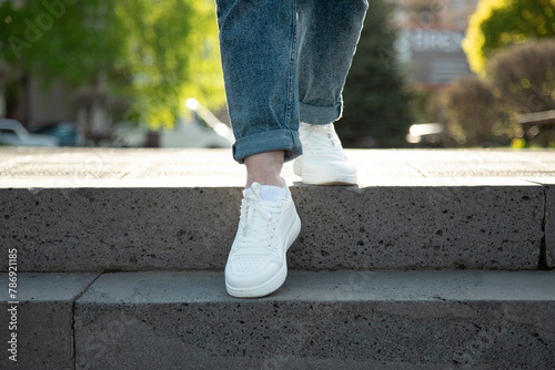 Photos Female legs in  white summer   sneakers and rolled up jeans descending the stairs in the city