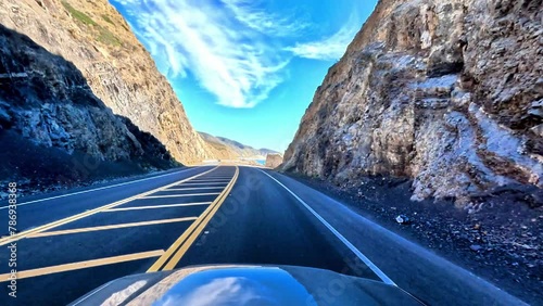 Immersive, establishment point of view of a cruise down the classic Pacific Coast Highway 101 to Malibu, California.  Enjoy scenes of sun, sand and surf below the bright blue skies. photo