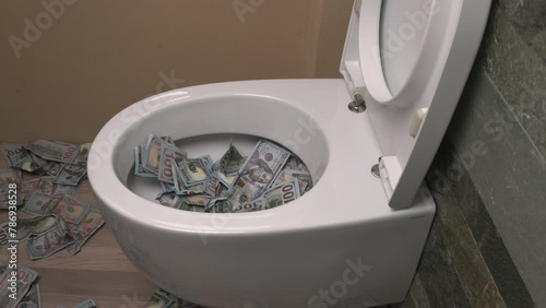 Throwing one hundred dollar bills down the toilet, slow motion. Concept of loss of money, bad investment.