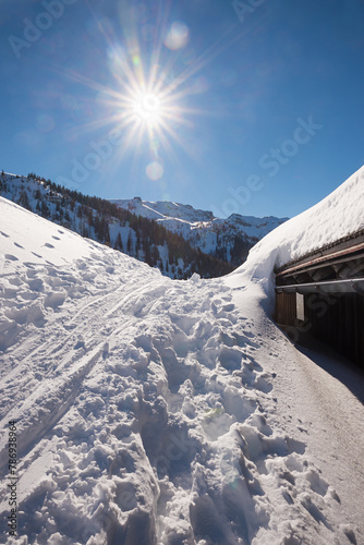 winter landscape tyrol, skiing tracks and snowbound hut, bright sunshine