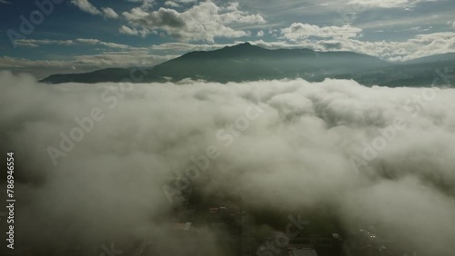 Drone view over Machachi city on a foggy sunny morning. Clouds floating around the Pasochoa volcano on the horizon. Pichicnha province, Ecuador photo