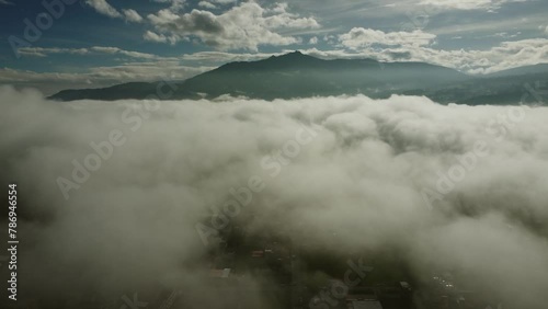 Drone view over Machachi city on a foggy sunny morning. Clouds floating around the Pasochoa volcano on the horizon. Pichicnha province, Ecuador