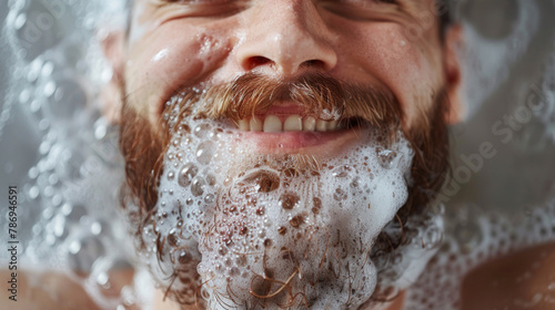 Happy, beard and man in bath with bubbles for clean, health and skincare routine with body hygiene. Smile, mouth and closeup of person with facial hair washing in water with foam for wellness at home photo