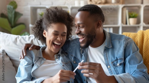 German couple sit excitedly on their couch, smiling and holding a pregnancy test. They are becoming parents and cannot wait for the new bundle of joy. photo