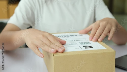 Close-up Shot of Professional Warehouse Worker Checks and Seales Cardboard Box Ready for Shipment. In the Background Rows of Shelves with Cardboard Boxes with Ready Orders. photo