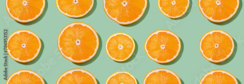 Pattern of orange slices against green background, top view, flat lay, copy space, banner, space for text, backdrop, wallpaper