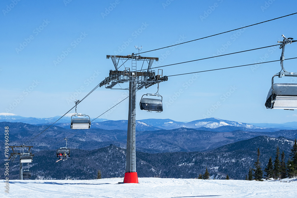 Chairlift in mountains during sunny winter day.