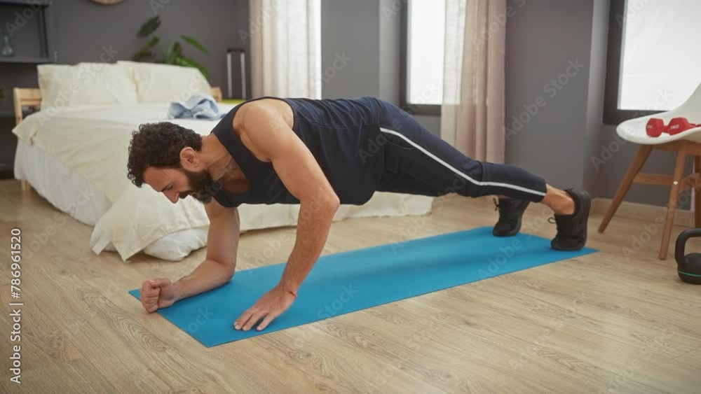 Man exercising plank position on yoga mat in bedroom interior, maintaining fitness routine at home Man exercising plank position on yoga mat in bedroom interior, maintaining fitness routine at home