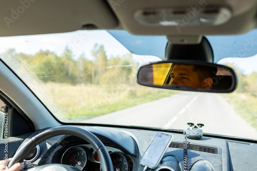 A man in a car checks the road using a navigator from a mobile phone