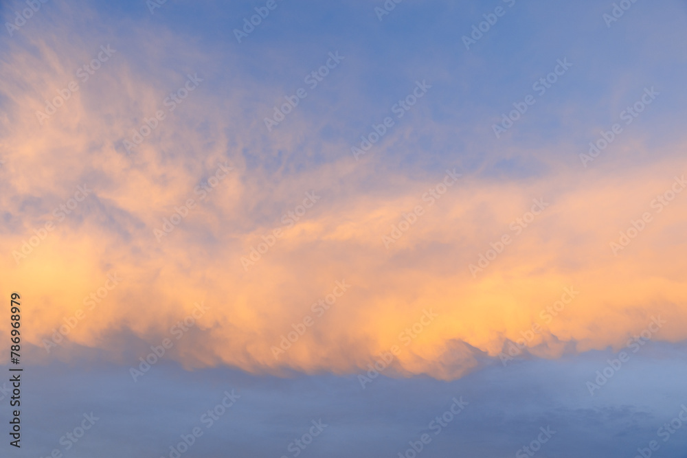 A serene sunset sky, awash with vibrant shades of orange and blue, creates a captivating backdrop, ideal for sky replacement or as a standalone piece in creative projects