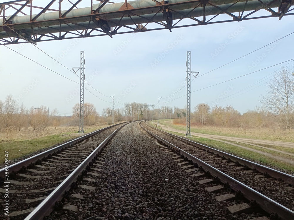 Two way railroad tracks and concrete bridge in countryside. Two railway tracks. Cloudy day. Countryside. Fields and trees.