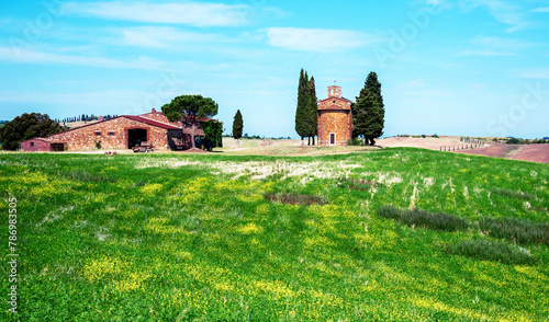 charming landscape with chapel of Madonna di Vitaleta near rape field  on a sunny day in San Quirico d'Orcia (Val d'Orcia) in Tuscany, Italy. Excellent tourist places.