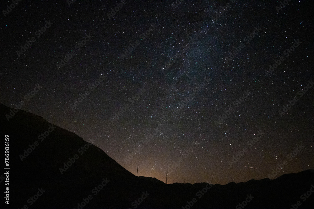 Milky way over the silhouette of the hills and city lights at night