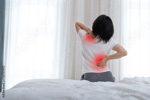 Women with backache sitting by the bed