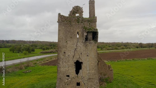 Aerial pullback captures Srah Tower in Tullamore, showcasing surrounding fields and canal. Symmetrical composition.