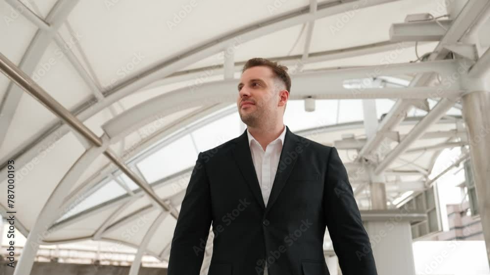 Skilled business man looking watch while walking to train station for going to workplace at bridge. Caucasian manager checking time for important appointment and walk along modern urban city. Urbane.