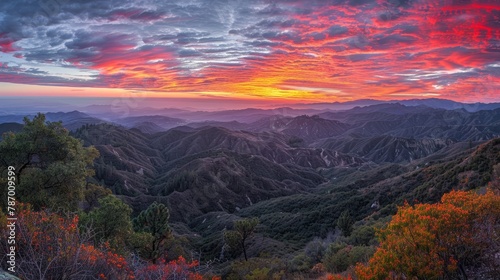 A tranquil early morning with vibrant hues painting the sky over a mountain range in panoramic sunrise