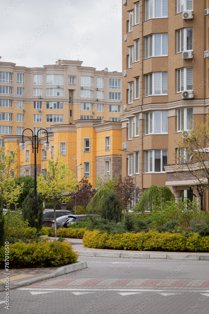Sofiivska Borshchahivka, Ukraine. April 16, 2024 Good variety of houses in residential complex. gray cloudy sky and flowering trees in the area. many cars are parked and people are walking.