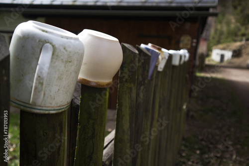 Ceramic mugs and pots on a wooden fence in the village close-up