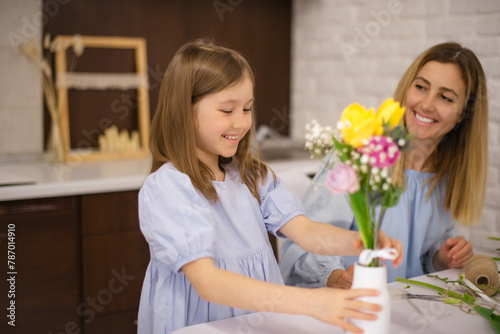 daughter puts bouquet of flowers in vase for mom on mother's day