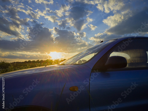 car at sunset, blue car in nature at sunset in the rays of the sun