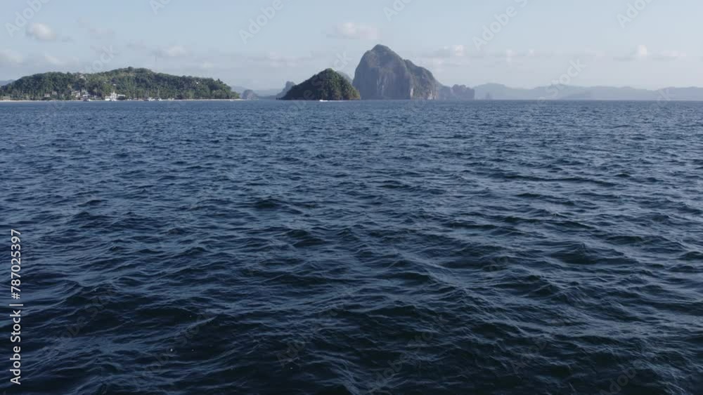 Low flying drone over water with tropical island in distance Low flying drone over water with tropical island in distance