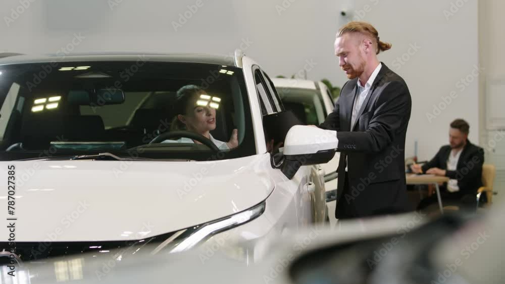 Demonstration of a modern service for renting new cars or test driving a car. A car dealership manager or salesman is consulting a client or buyer. Demonstration of a modern service for renting new cars or test driving a car. A car dealership manager or salesman is consulting a client or buyer.