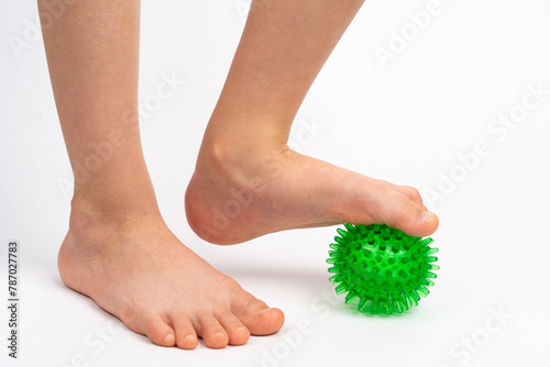 green needle ball for massage and physical therapy on a white background with a child's foot, the concept of prevention and treatment of foot valgus