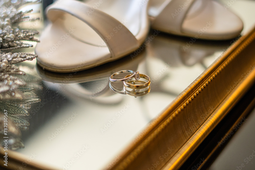 A close-up of delicate bridal details, including a sparkling tiara, white shoes, and wedding rings, perfect for a bridal or wedding blog