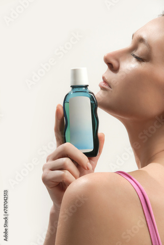 Close up of woman holding bottle with skincare cosmetic product