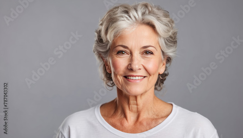 Beautiful mature woman with light grey background in a white t-shirt, studio shot 

 photo