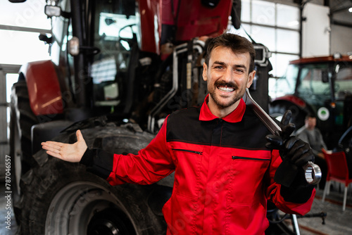 Professional mechanic servicing and maintaining tractor agricultural vehicle.